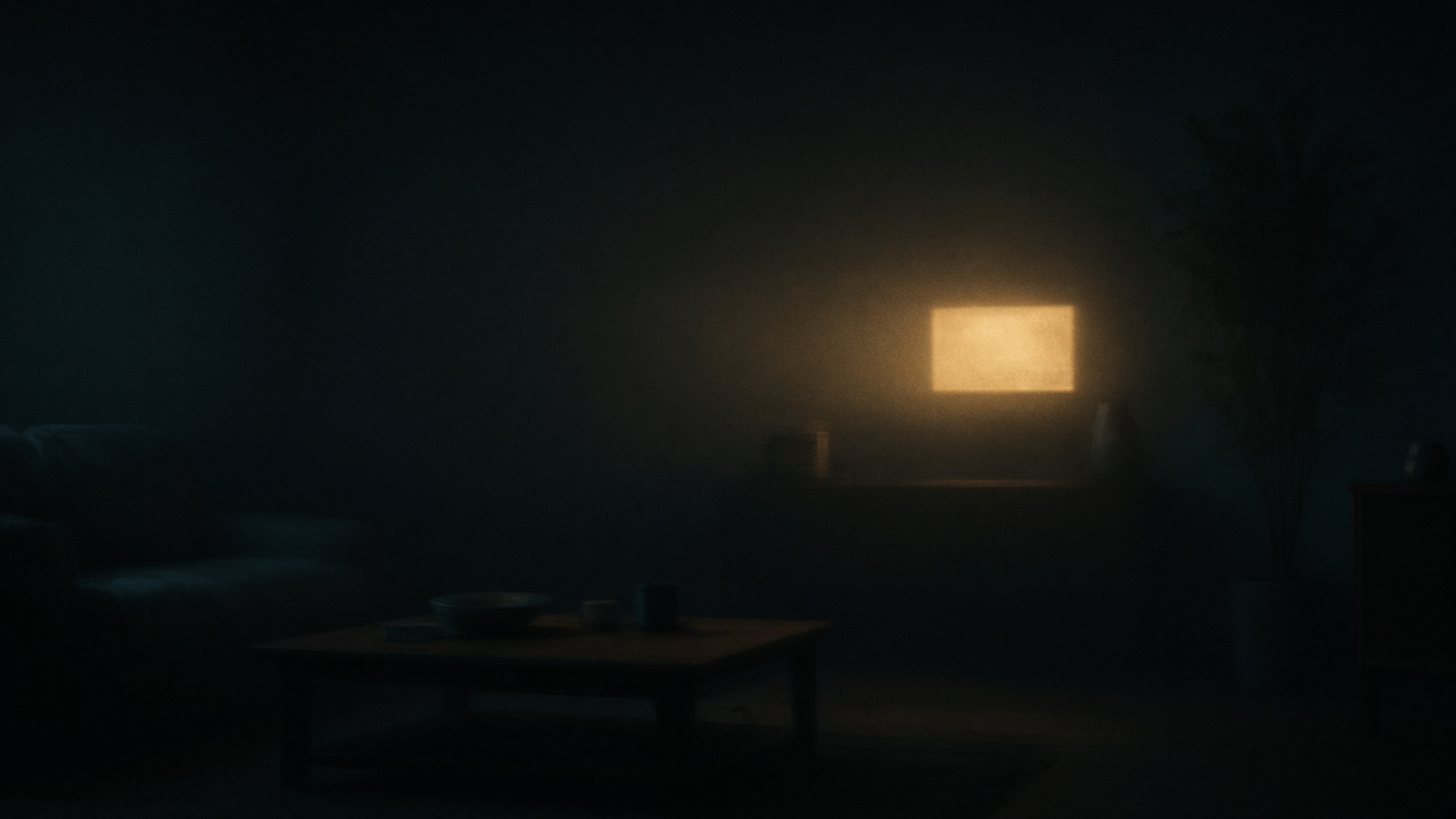 A dark room. One champagne-gold aperture of light. No faces.